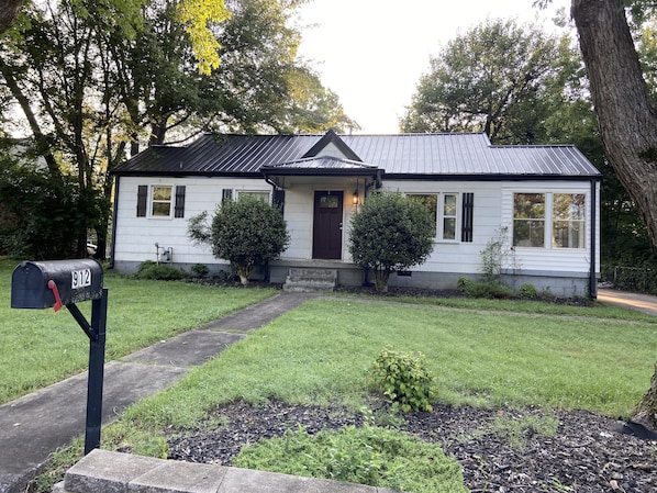 Welcome to a charming single-story home with a well-manicured lawn and a cozy porch.