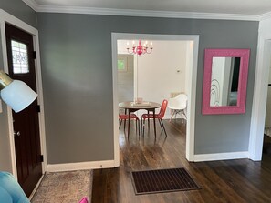 Stylish hallway leads to a dining area with a modern chandelier and a decorative mirror.