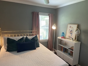 Relax in this serene bedroom with a plush bed, bedside table, and potted plant.