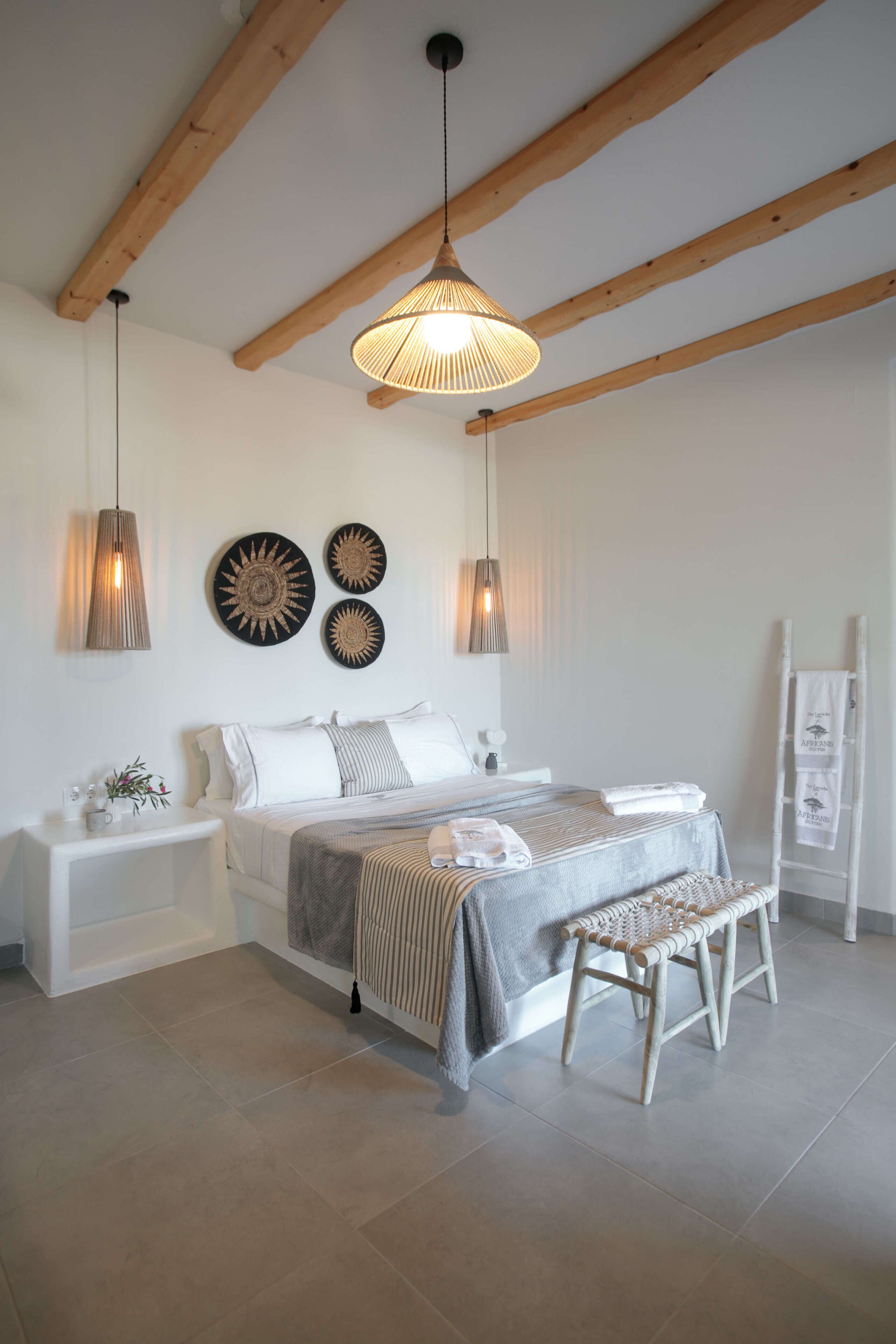 A bedroom with a bed, bedside tables, a bench, a ladder, and wall decorations.