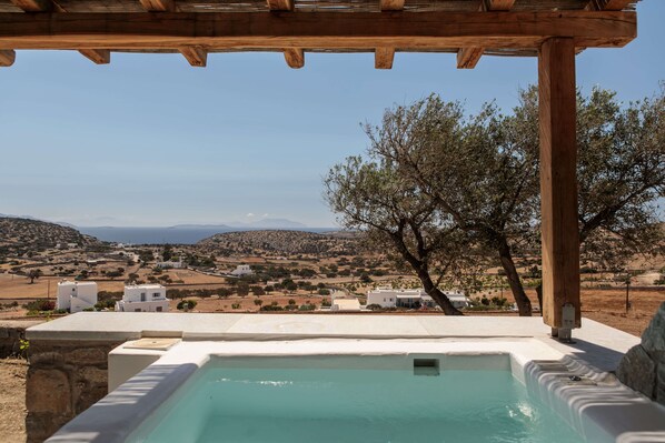 Un espace piscine offrant une vue sur un paysage rural, avec des maisons et des collines.