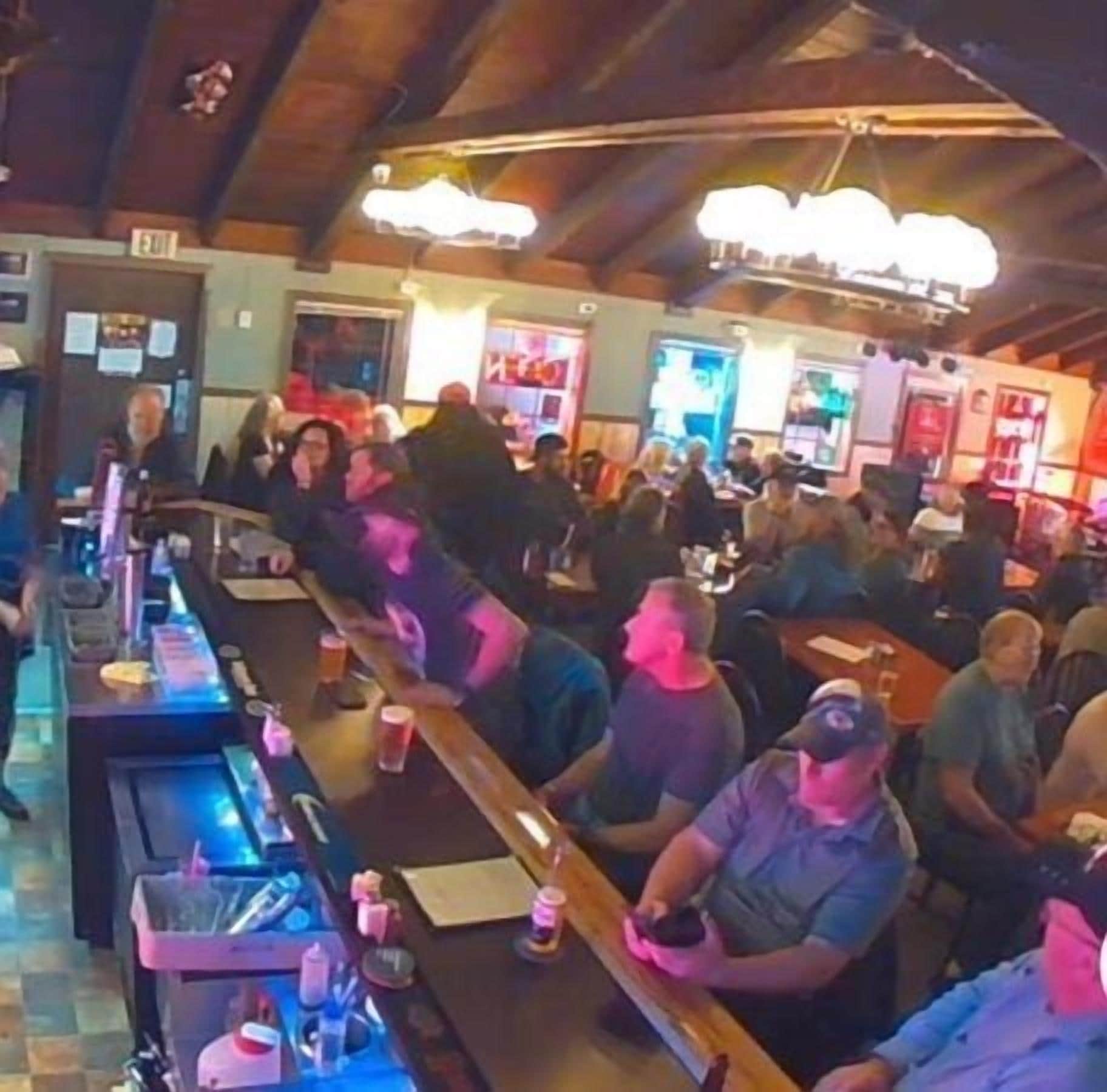 Un bar affollato con banconi in legno e clienti seduti ai tavoli.
