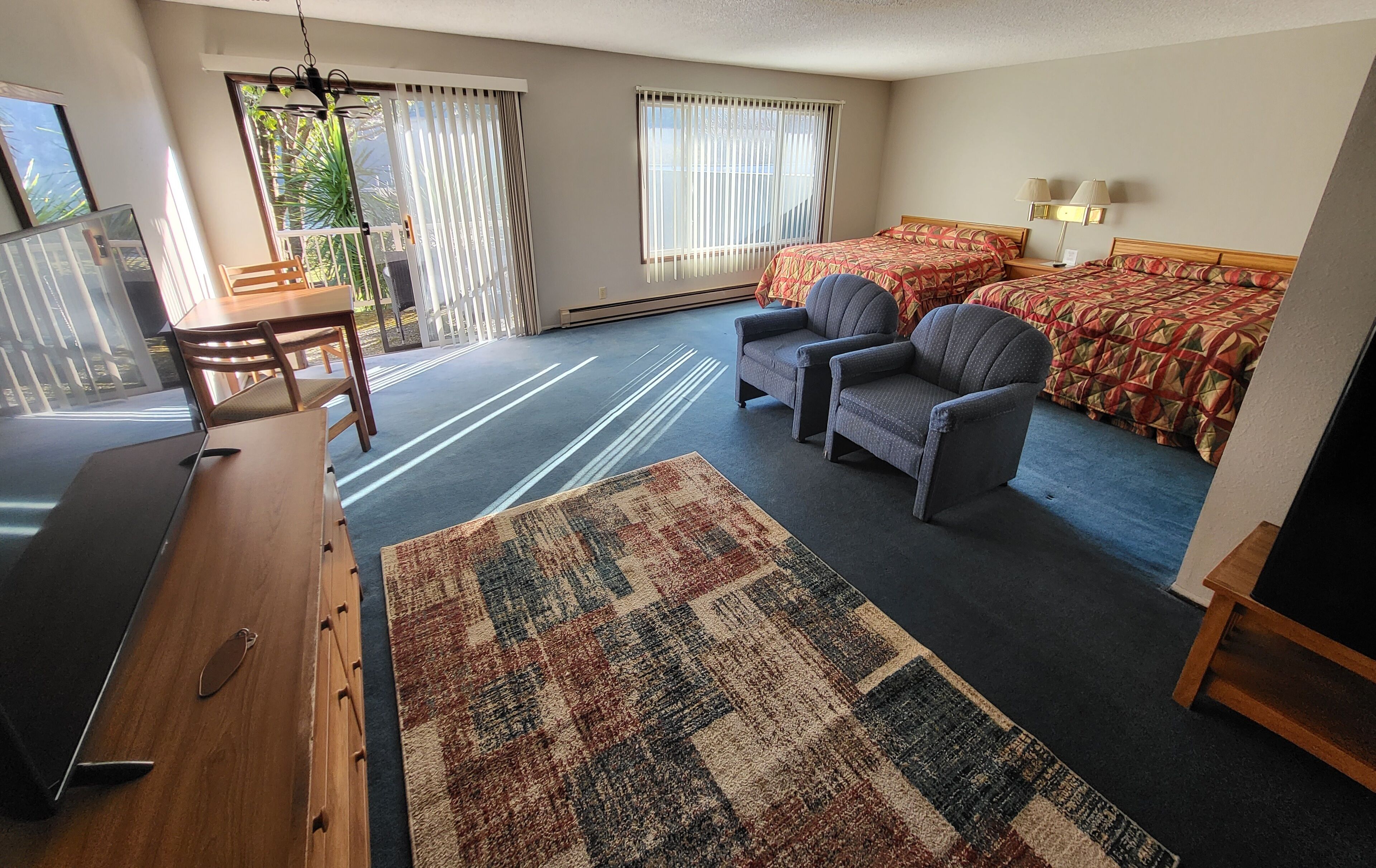 A hotel room with a bed, two armchairs, a desk, and a small table.