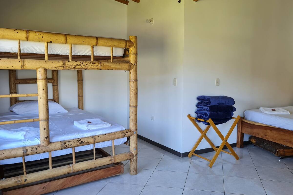 A room with two bunk beds and a single bed, wooden furniture, and a folded towel on the floor.