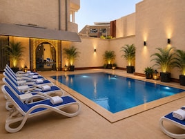Una piscina con sillones de descanso y plantas en macetas.