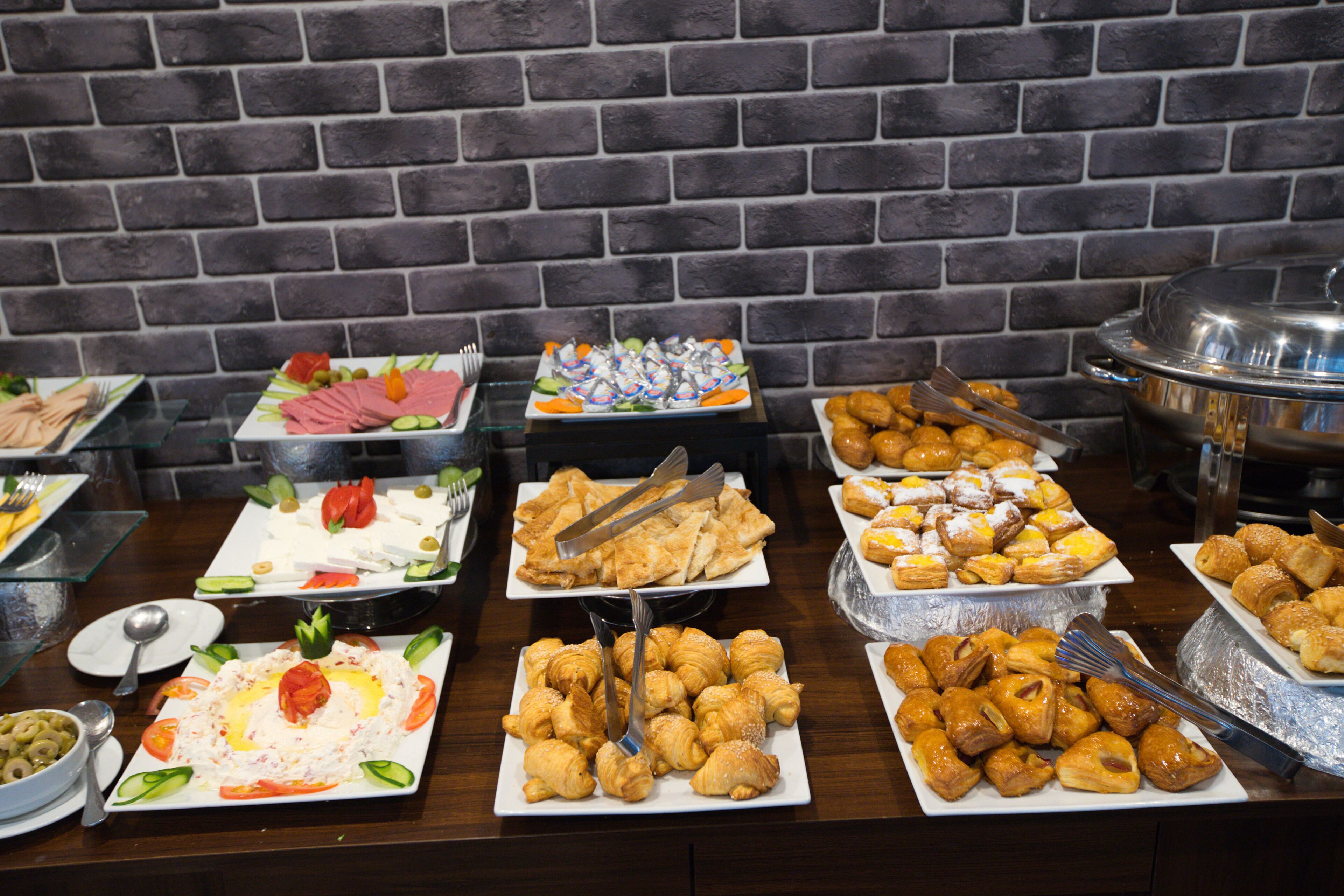 Un bufé con diversos alimentos, como ensaladas, pasteles y carnes.