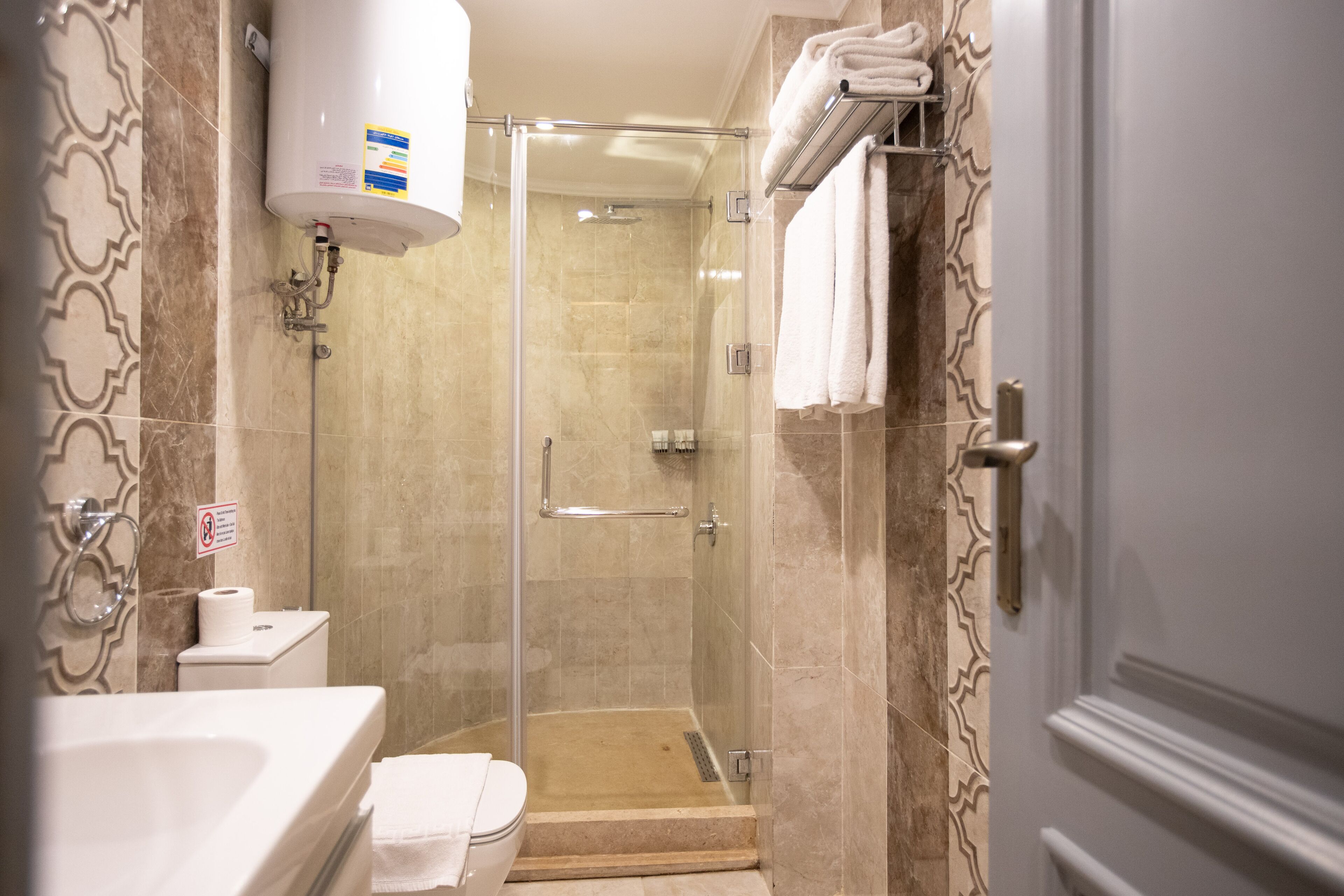 A bathroom with a glass-enclosed shower, a toilet, and a sink.