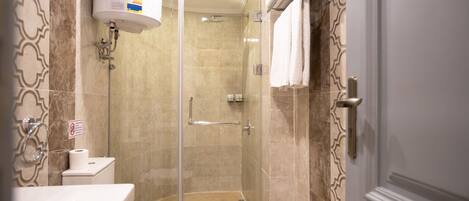 A bathroom with a glass-enclosed shower, a toilet, and a sink.