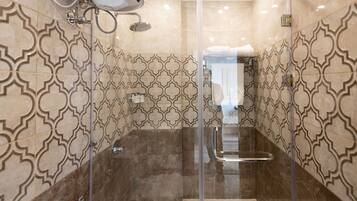 Un baño moderno con cabina de ducha de vidrio, azulejos estampados y un perchero visible.
