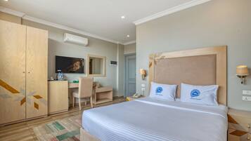 Een hotelkamer met een groot bed, een bureau, een stoel, een kledingkast en een televisie.