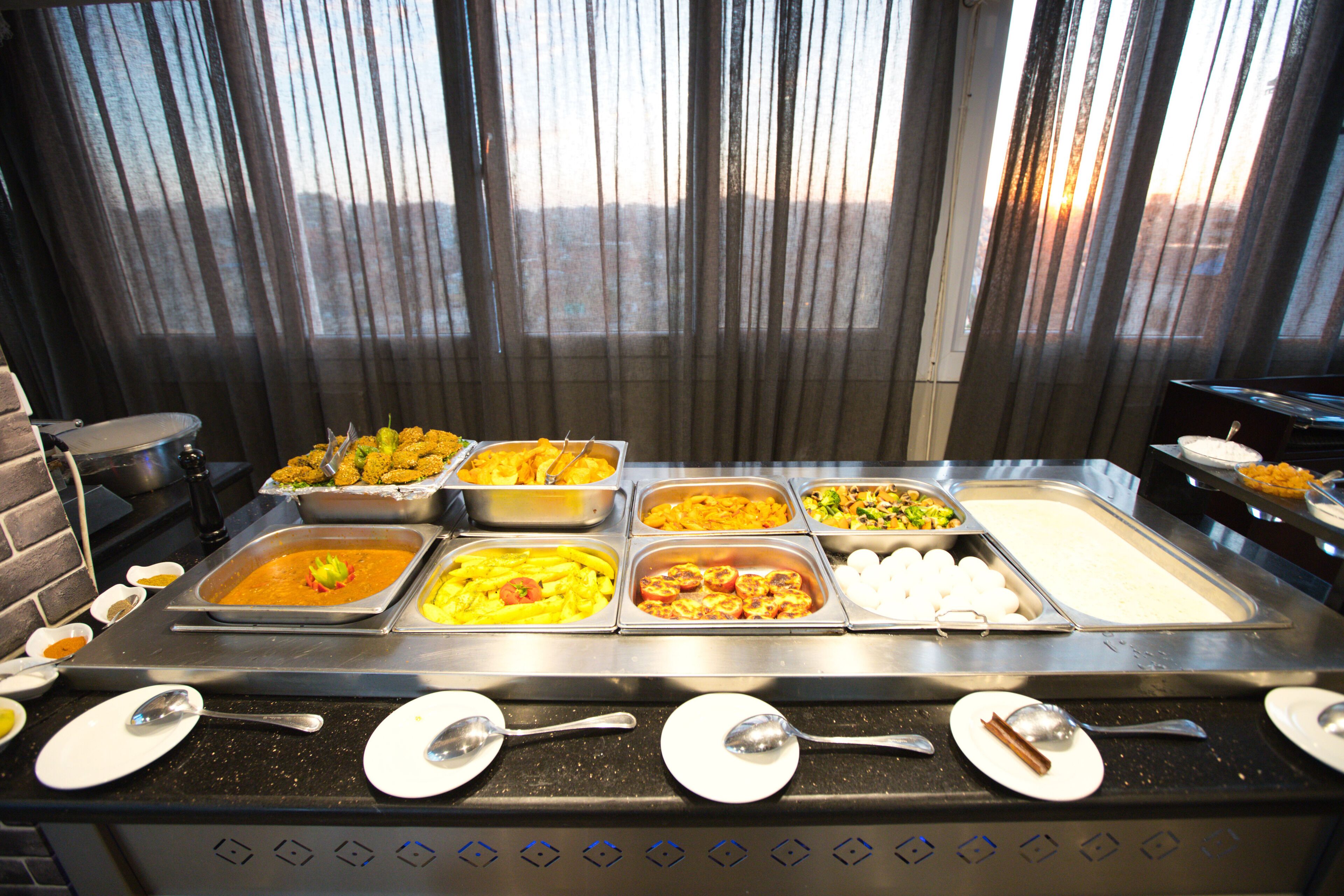 A buffet with various food options and serving utensils.
