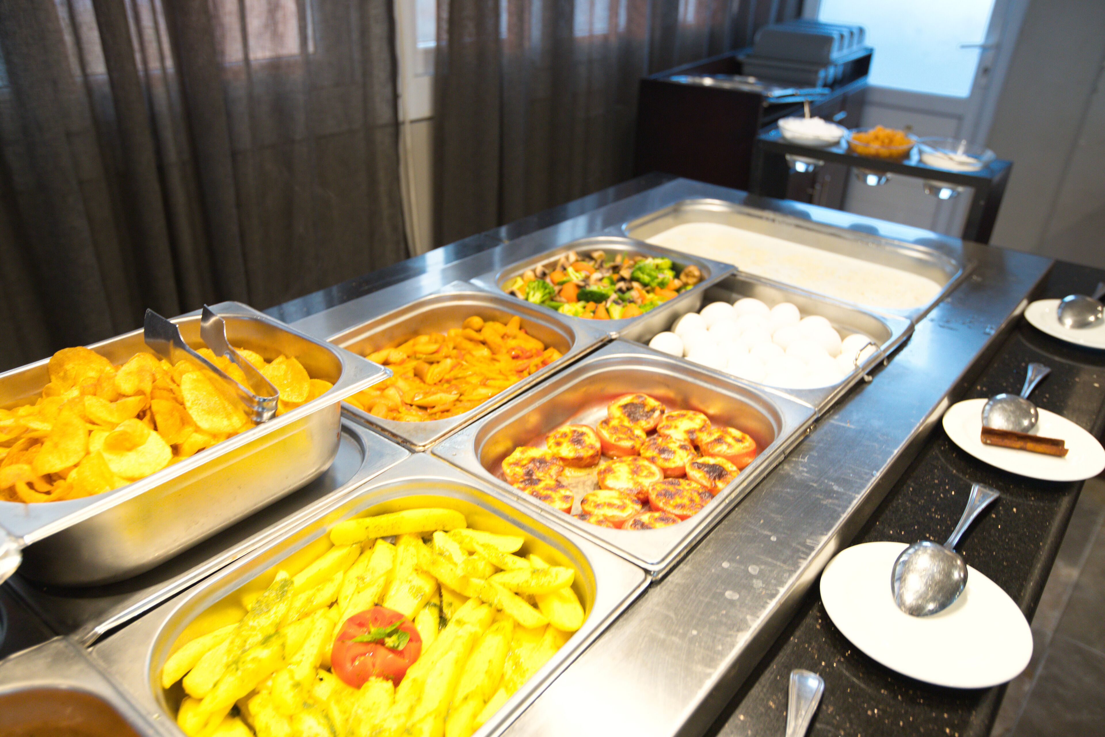 Un bufé con diversas opciones de comida, incluyendo pasta, verduras y huevos.