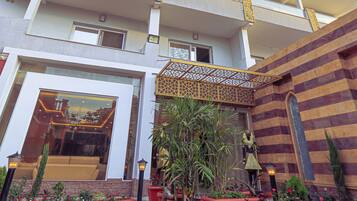 A hotel with multiple balconies, a central courtyard with potted plants, and a modern architectural design.
