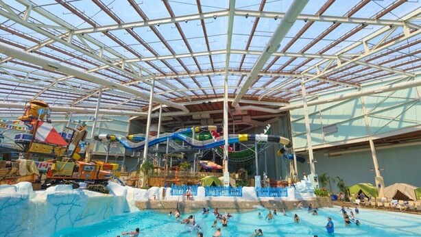 Een overdekt waterpark met meerdere zwembaden en glijbanen, en een grote waterglijbaan.