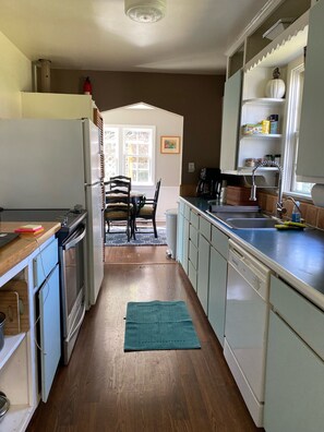 Une cuisine équipée d’un réfrigérateur, d’une cuisinière, d’un évier et d’une table à manger en bois avec des chaises.