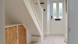 A staircase with white balusters leading to a landing, a white door with a window, and a wooden cabinet. - 2 bedroom accommodation in Silverdale (Silverdale)