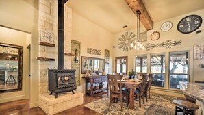 Cocina acogedora con chimenea de piedra, mesa de comedor de madera y amplias ventanas.
