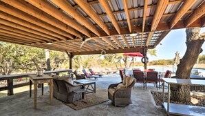 Un patio al aire libre con vigas de madera, muebles de mimbre y una mesa con sombrilla roja.
