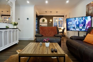 A modern living room with a wooden coffee table, two sofas, a TV, and a fireplace.