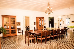 A dining area with a large wooden table surrounded by chairs, a chandelier, and a patterned floor.