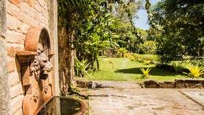 A courtyard with a fountain, brick pathway, and lush greenery. - Estâncias Duvivier Hotel (Tres Rios)