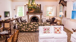 A cozy living room with a fireplace, a sofa, a chair, and a dining table. - Estâncias Duvivier Hotel (Tres Rios)