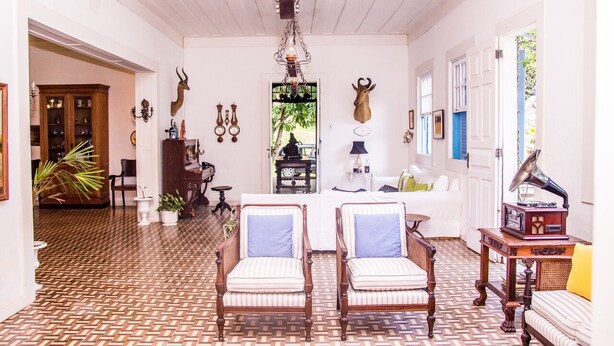 A spacious room with patterned flooring, a chandelier, and a seating area with two armchairs and a sofa. - Estâncias Duvivier Hotel (Tres Rios)