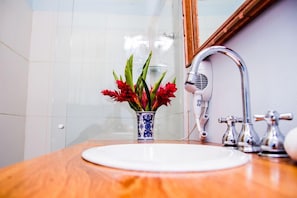 A bathroom with a white sink, a blue and white vase with red flowers, and a modern faucet.