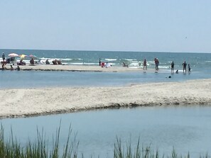 Een strand met mensen, parasols en een rustige zee.