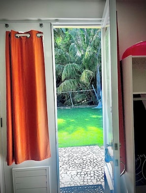 A room with a sliding glass door leading to a patio with a tiled floor and a grassy area.