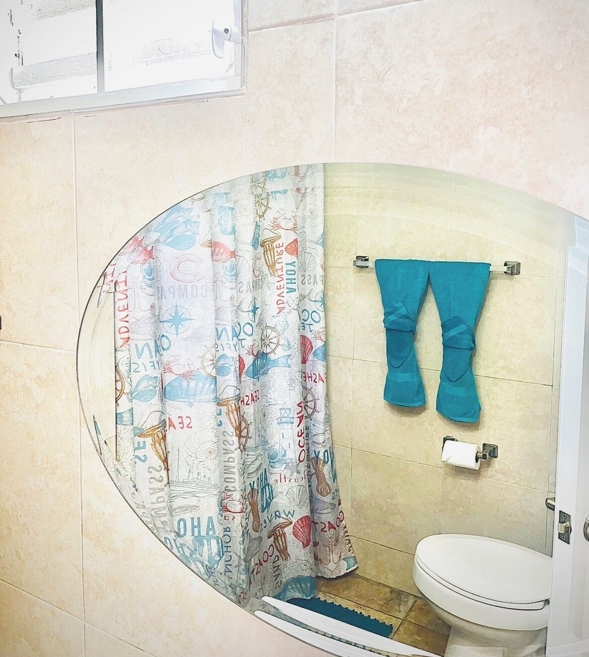 Casa de banho com cortina de chuveiro curva, sanita e porta-toalhas com toalha.