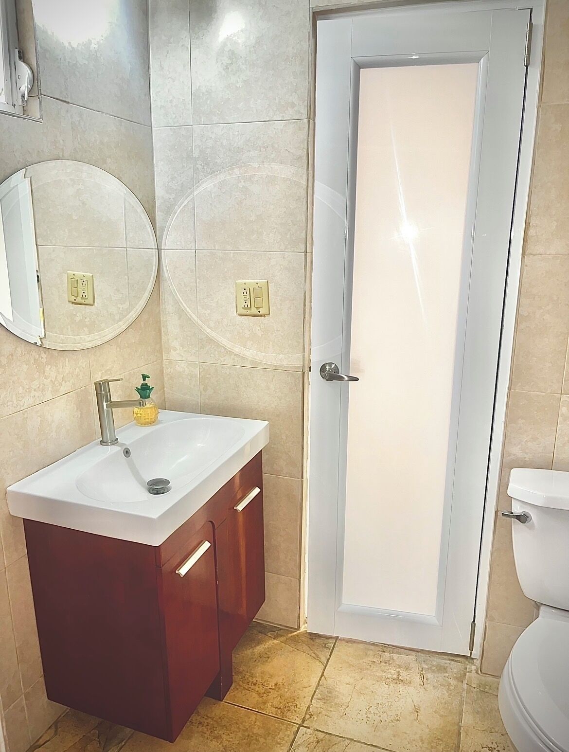 A bathroom with a white sink, wooden vanity, two wall-mounted mirrors, and a white toilet.