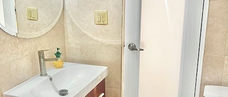 A bathroom with a white sink, wooden vanity, two wall-mounted mirrors, and a white toilet.