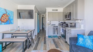 Una cocina moderna con armarios blancos, un lavavajillas de acero inoxidable y un televisor de pantalla plana sobre la encimera.