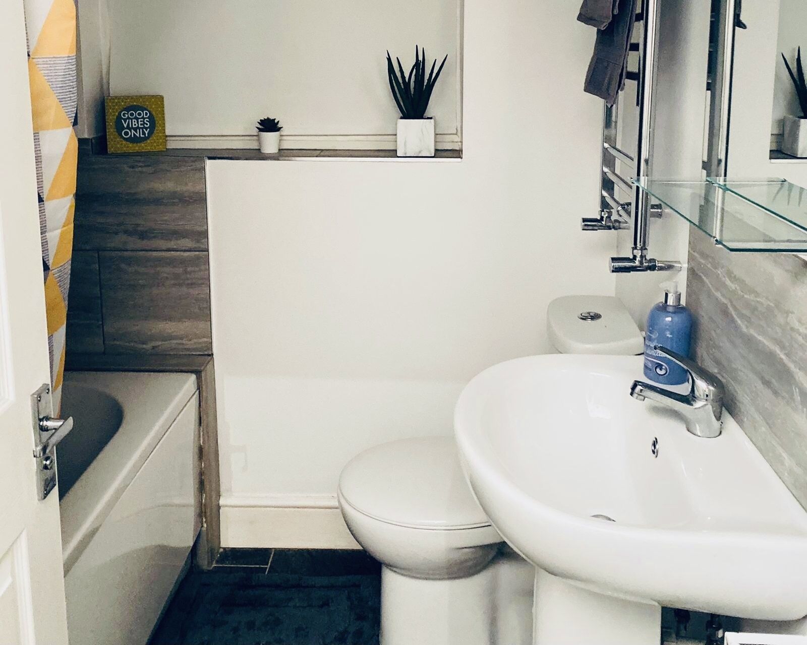Ein kleines Badezimmer mit Toilette, Waschbecken und einem kleinen Regal mit Pflanzen.