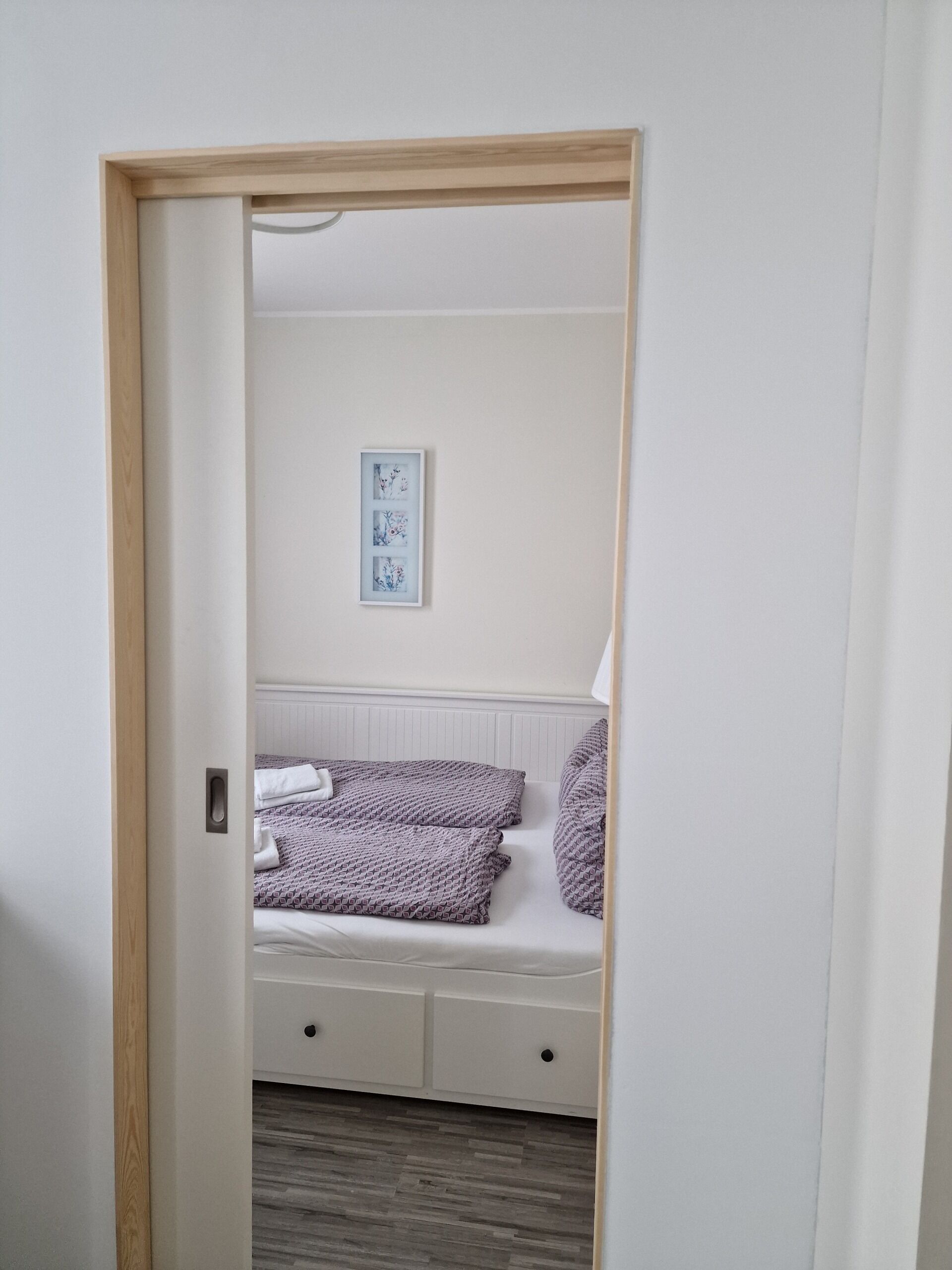 A bedroom with a bed, a bedside table, and a framed picture on the wall.