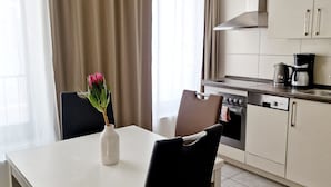 A modern kitchen with a dining area, featuring a white table, black chairs, and a hanging pendant light. - Domblick Schwerin (Schwerin)