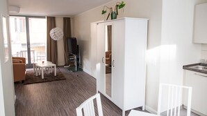 A modern, well-lit living area with a sofa, a dining table, and a kitchen area with a sink and cabinets. - Domblick Schwerin (Schwerin)