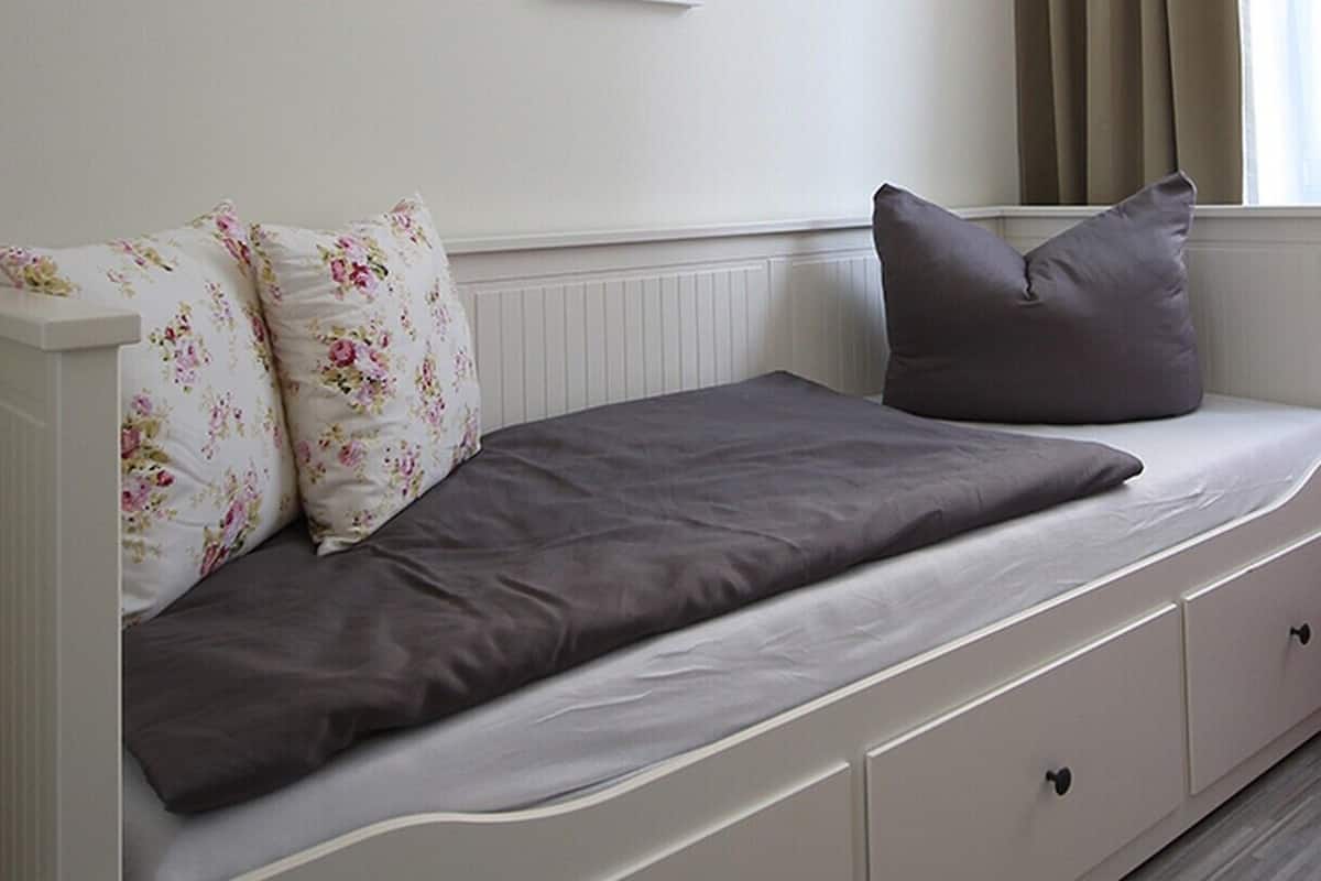 Una habitación con una cama, una silla roja y una ventana con cortinas.