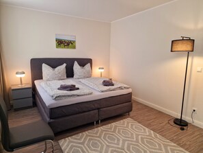 A neatly arranged bedroom with a bed, two bedside tables, a floor lamp, a rug, and a picture on the wall. - Domblick Schwerin (Schwerin)