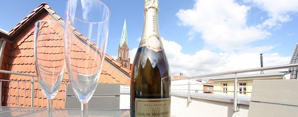 A bottle of Louis Roederer Brut Premier wine and a glass on a balcony with a view of a church and buildings. - Domblick Schwerin (Schwerin)
