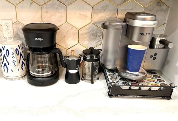 A coffee station with a Mr. Coffee maker, a Keurig, a French press, and a coffee grinder.