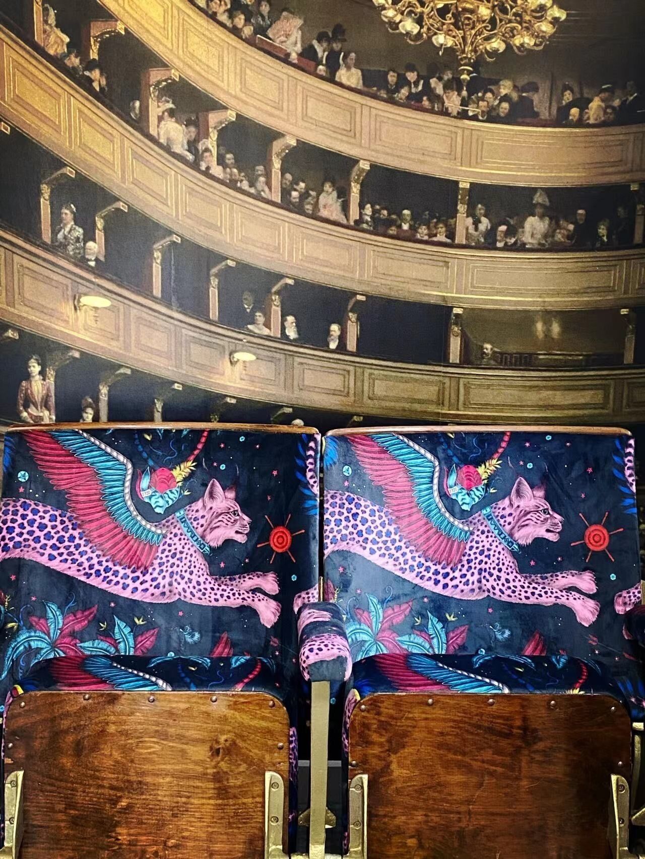 A theater with ornate, curved balconies and rows of seats featuring a colorful, celestial-themed design.