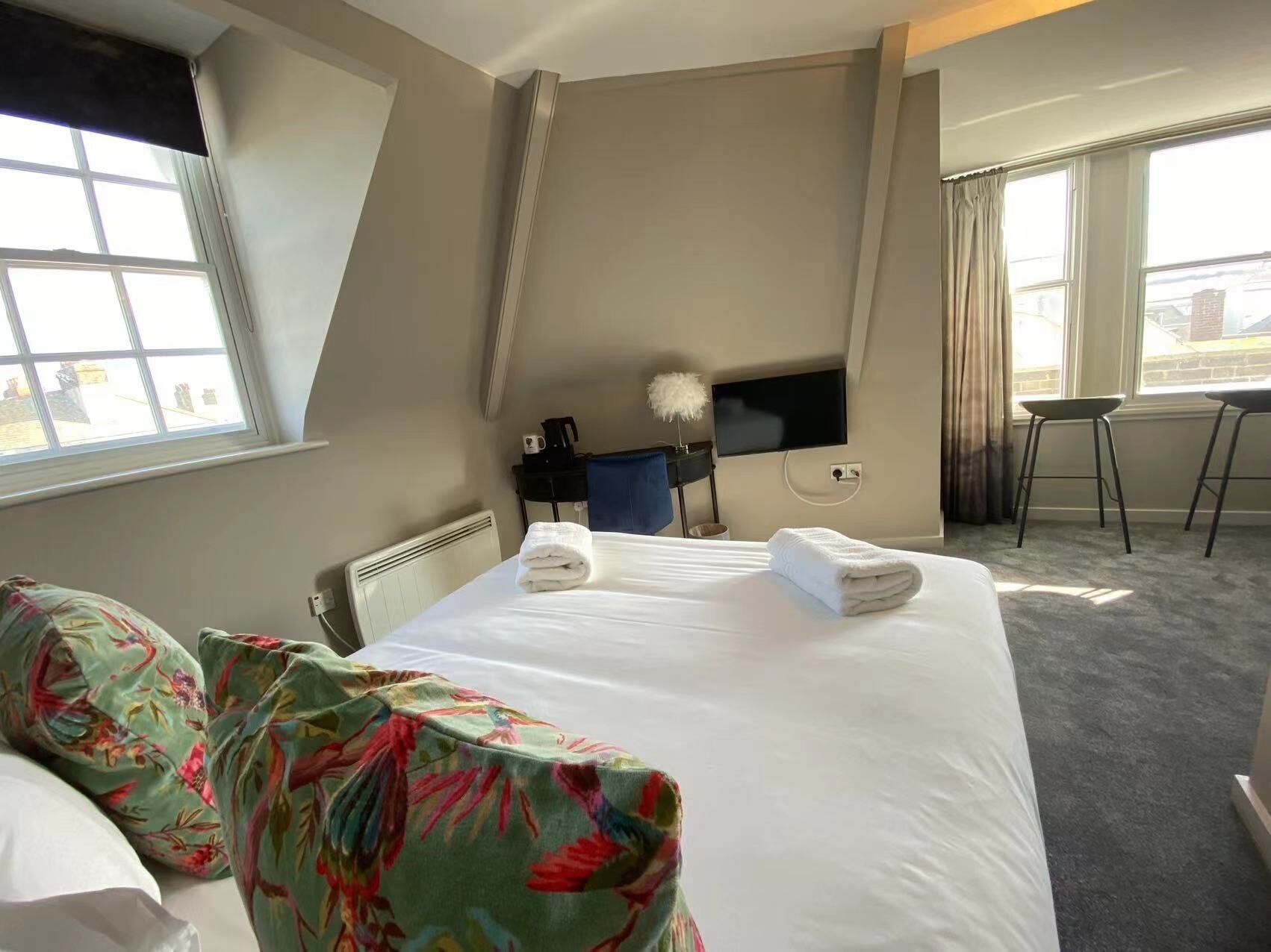 Ein Hotelzimmer mit Bett, Schreibtisch, Fernseher und einem Fenster mit Vorhängen.