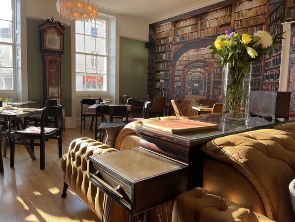 A library with bookshelves, a clock, and a vase with flowers.