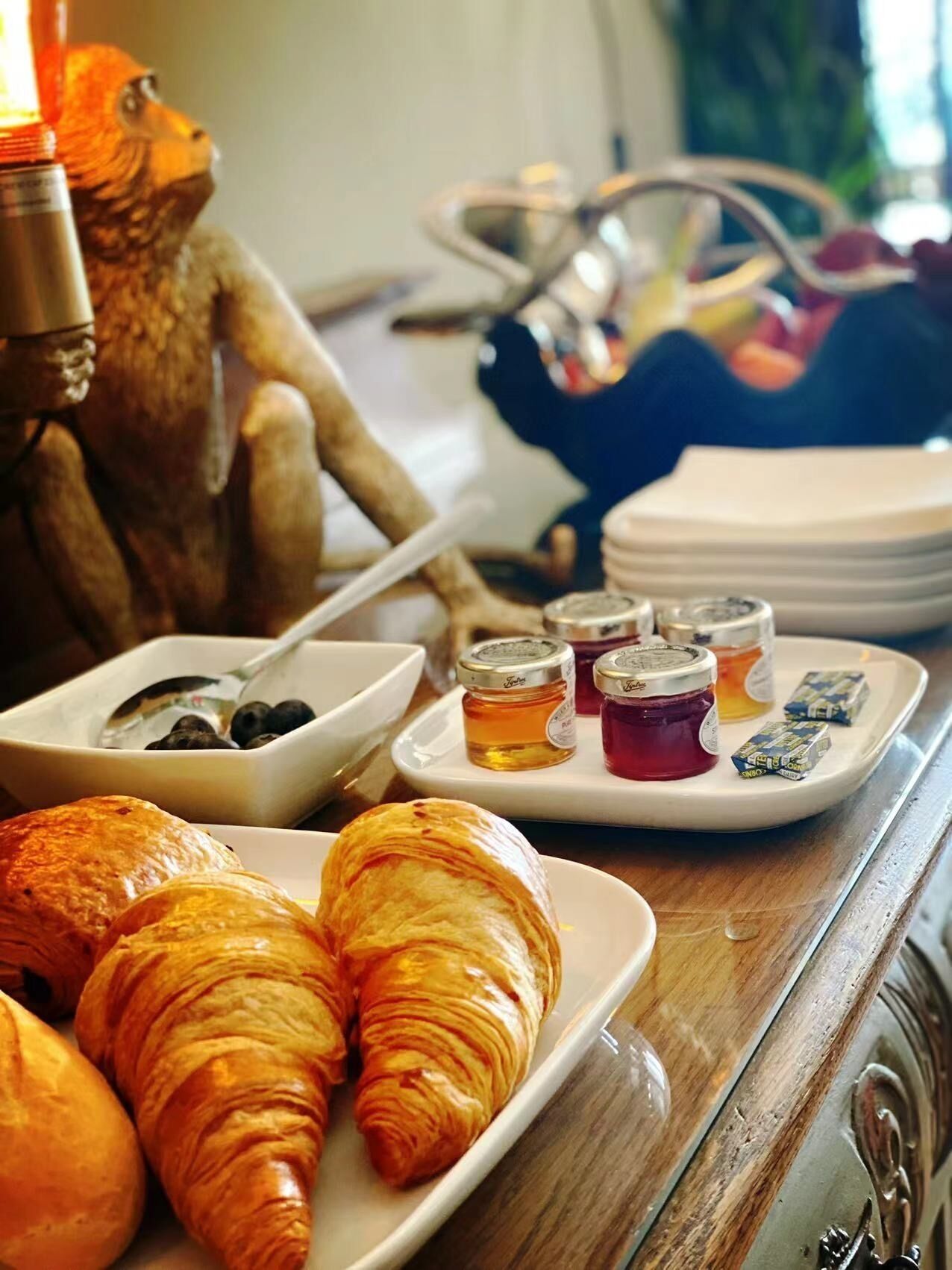 Een ontbijtsetting met croissants, honingpotjes en een decoratief dierenfiguur.