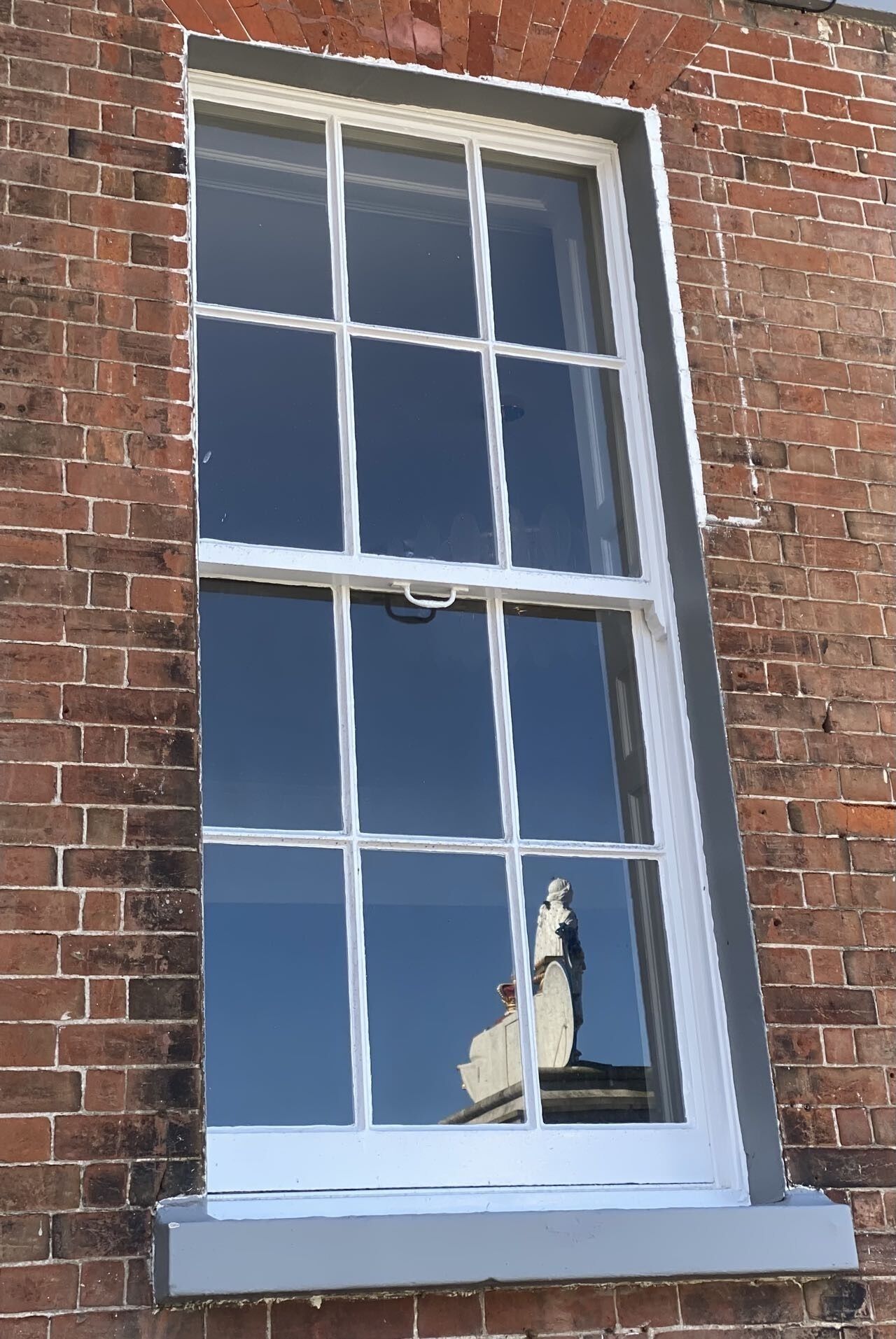 A window with a white frame and six panes, set in a brick wall.