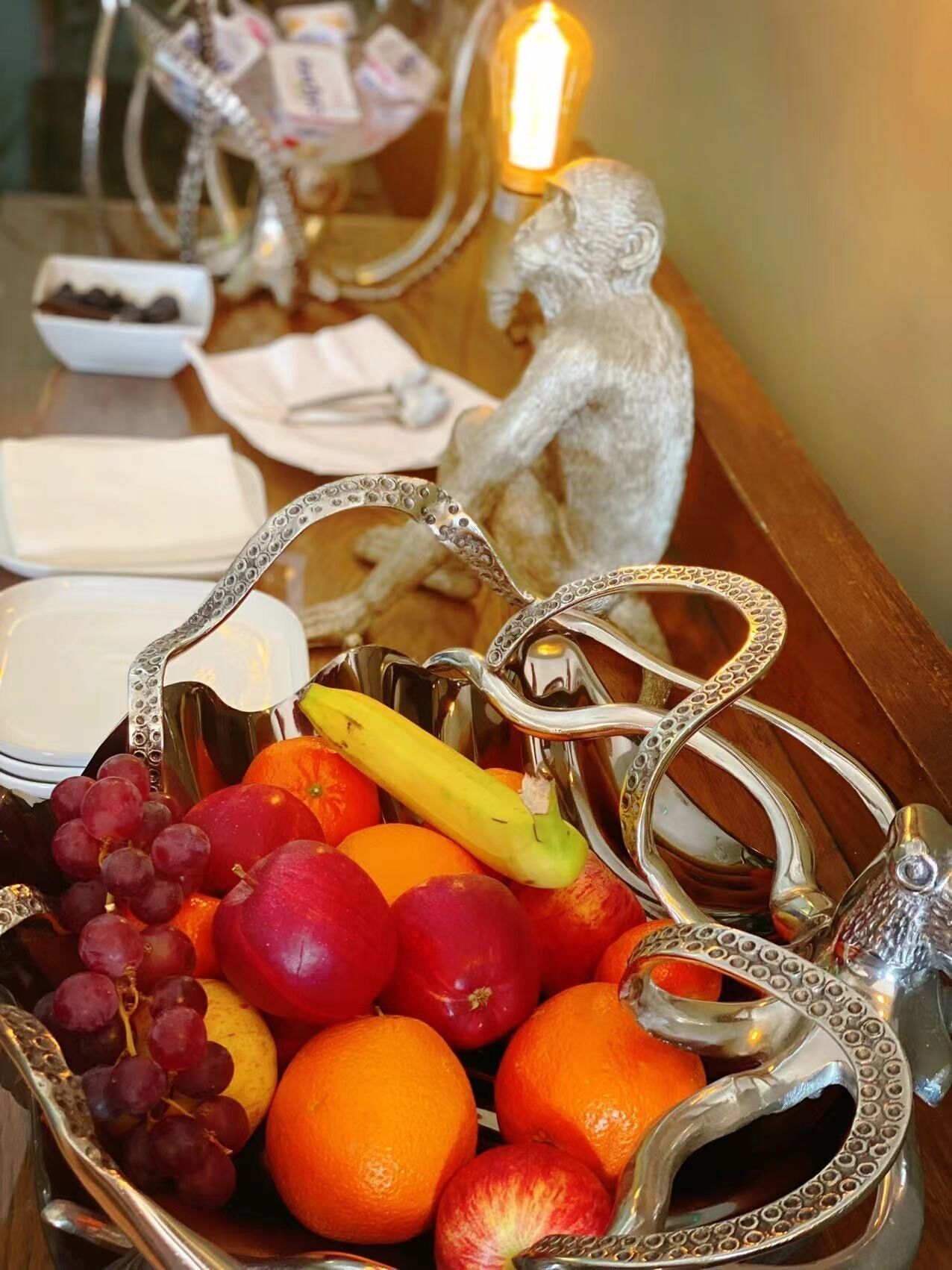 A fruit basket with grapes, apples, oranges, and a banana on a wooden table.