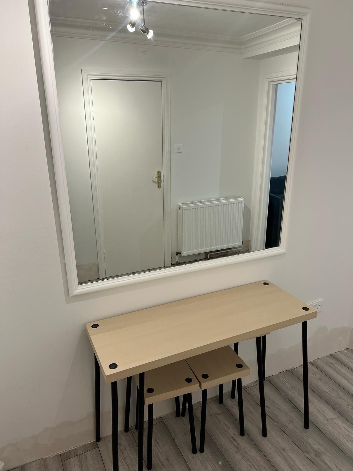 A room with a large mirror, a wooden table, and a radiator.