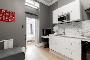 A modern kitchen with white cabinets, a marble countertop, and a built-in microwave. - Hotel Orlando by PLI (London)